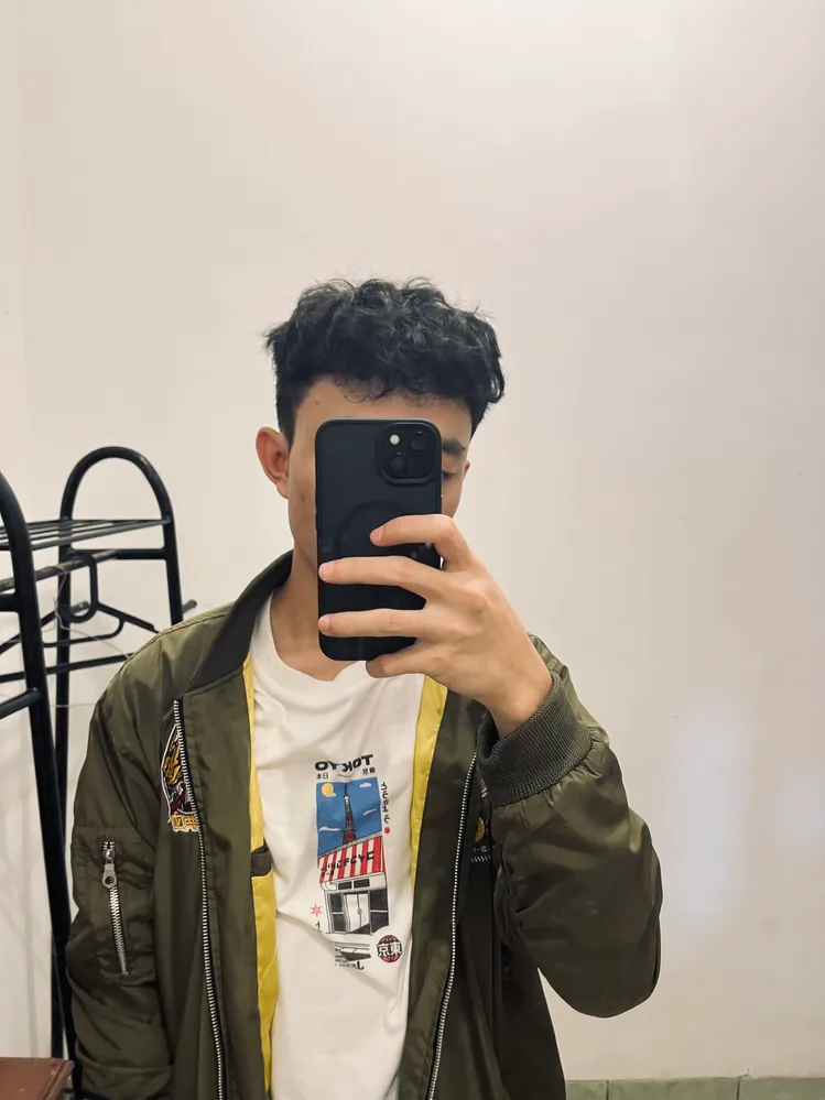 A mirror selfie of Rizki, wearing white shirt with sage green Jacket.